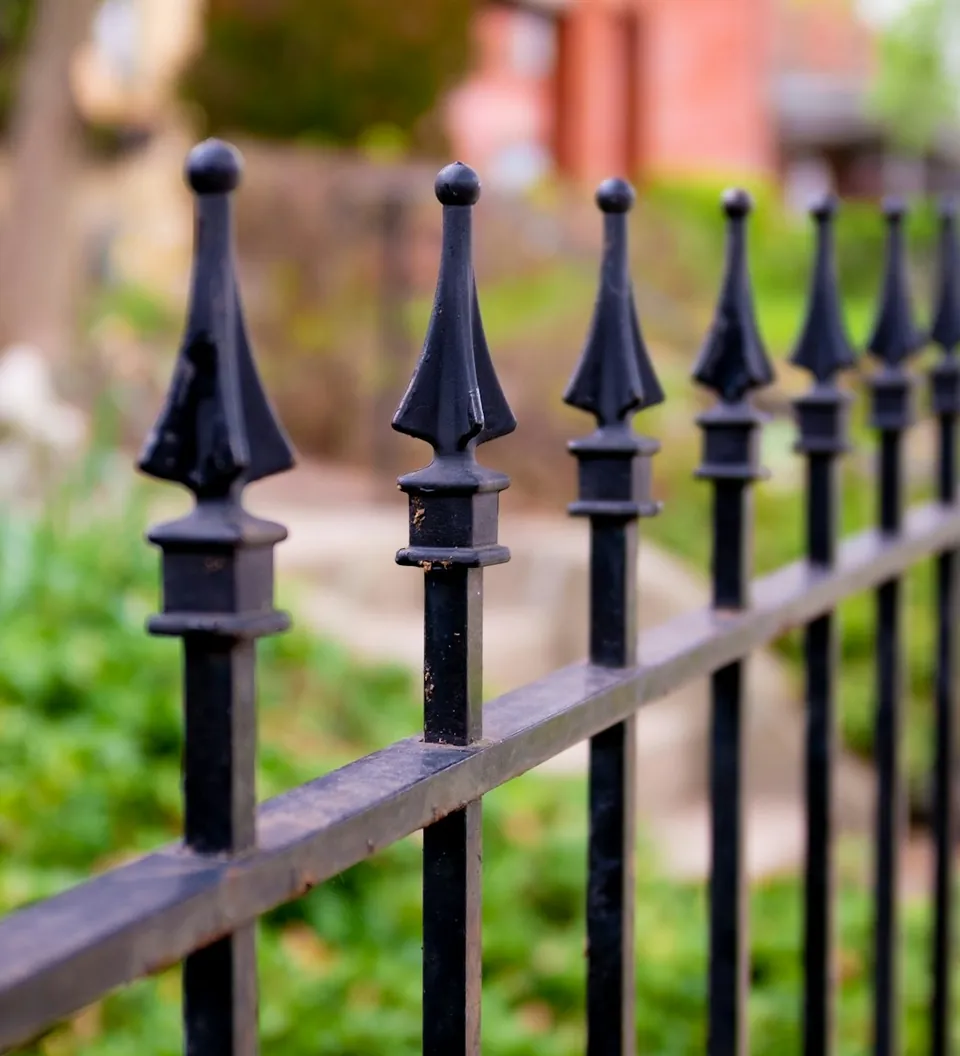 Rejas para locales en Estación Central Reja de fierro negro con puntas de lanza junto a un jardín