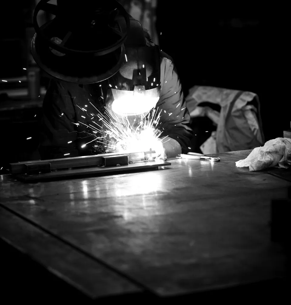 Soldador San Bernardo Soldador trabajando sobre una plancha metálica en blanco y negro